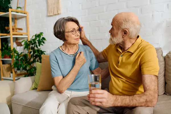 A devoted woman assists her husband with diabetes while they sit together comfortably at home. — Stock Photo