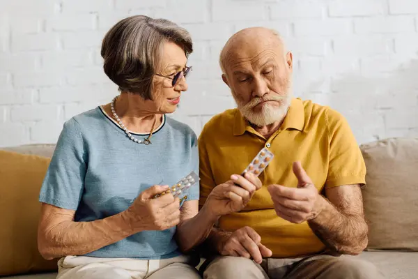 A caring wife helps her husband check his diabetes medication while sitting together. — Stock Photo