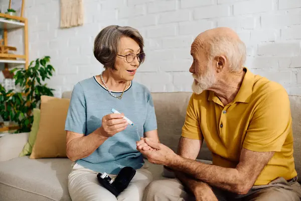 A devoted wife assists her husband in monitoring his diabetes at home, showcasing their love. — Stock Photo