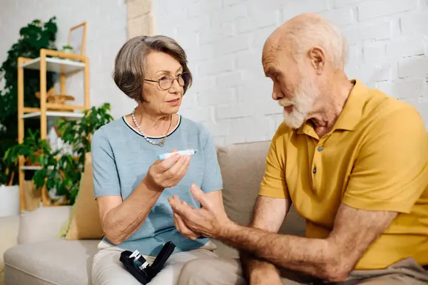 A senior woman assists her husband with diabetes management in their comfortable home. — Stock Photo