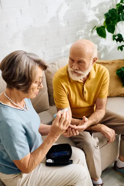 A devoted wife assists her husband with diabetes care in their cozy living room. — Stock Photo