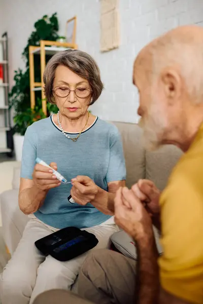 A devoted wife monitors her husbands blood sugar levels, showing love and support. — Stock Photo