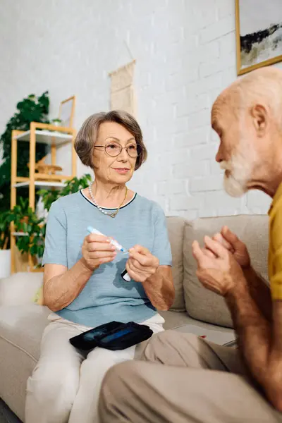 A devoted wife helps her husband manage his diabetes in their warm and inviting home. — Stock Photo
