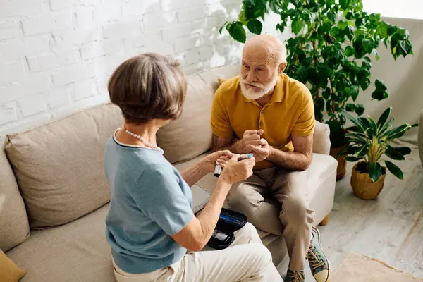 A devoted wife assists her husband, managing his diabetes with love and support at home. — Stock Photo