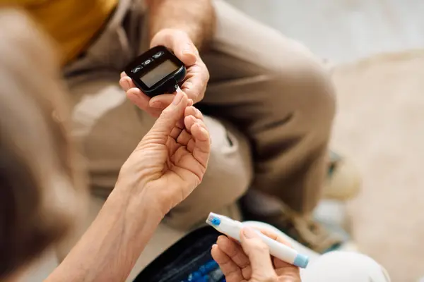 A senior couple shares a heartfelt moment as the wife assists her husband with diabetes management. — Stock Photo