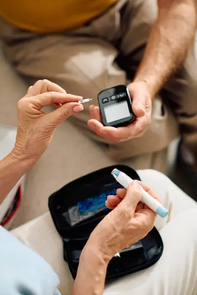 In un ambiente accogliente casa, una moglie devota assiste il marito con la sua gestione del diabete. — Foto stock