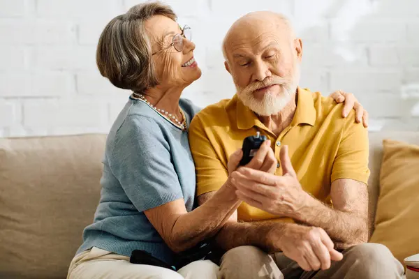 A caring wife assists her diabetic husband in their cozy living room, showcasing love and support. — Stock Photo