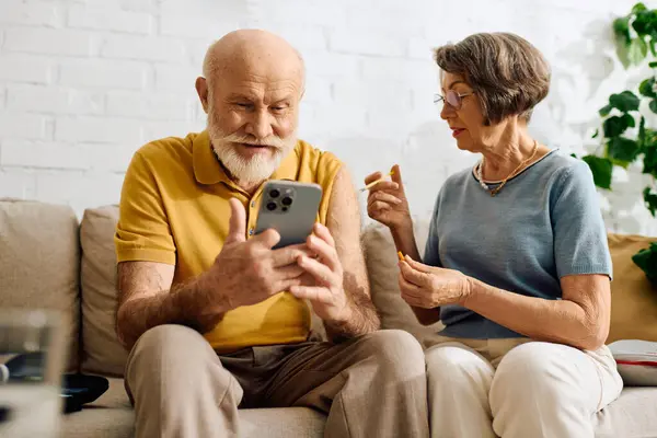 A devoted wife helps her husband with diabetes while they engage with his smartphone. — Stock Photo