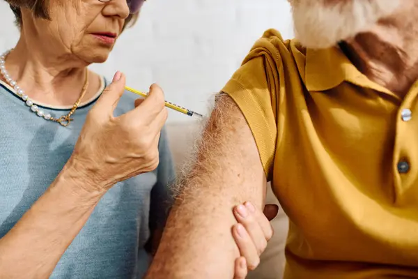 A devoted wife gently provides insulin to her diabetic husband in their cozy living room. — Stock Photo