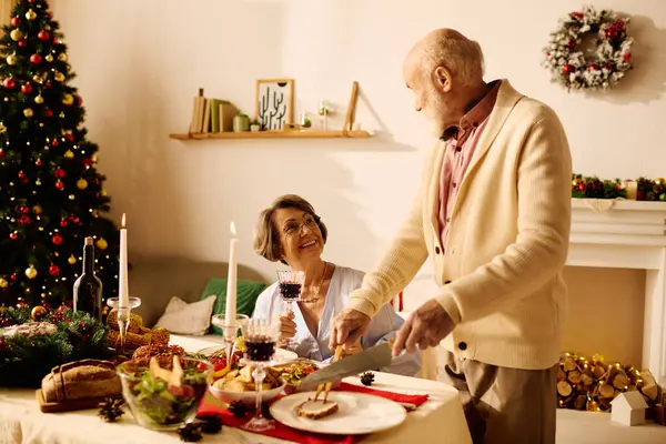 A happy elderly couple enjoys Christmas dinner at home, surrounded by decorations and love. — Stock Photo