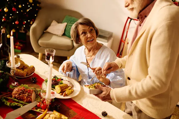 Una pareja cariñosa comparte una deliciosa comida de Navidad en casa, llena de risa y calidez. - foto de stock