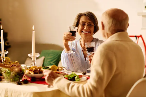 A joyful senior couple raises glasses filled with a festive drink, celebrating Christmas at home. — Stock Photo