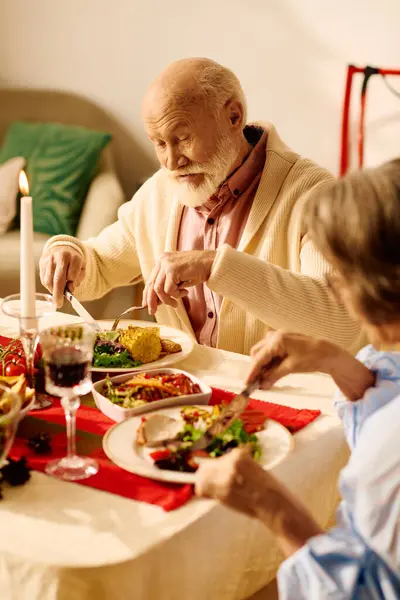 A loving senior couple shares a festive Christmas meal, surrounded by warmth and togetherness. — Stock Photo