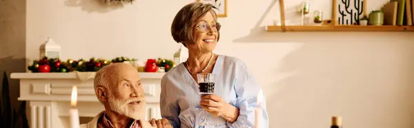 Una alegre pareja de ancianos disfruta de la compañía de los demás, celebrando la Navidad en su acogedora casa. - foto de stock