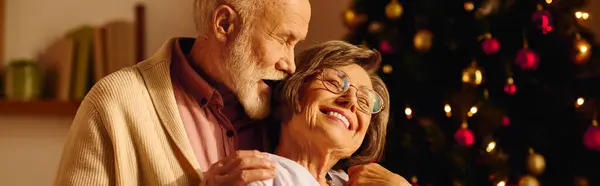 A loving senior couple celebrates Christmas together at home, surrounded by festive cheer. — Stock Photo
