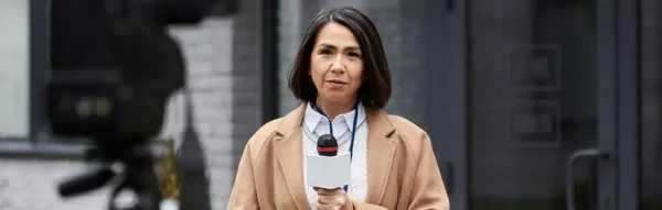 A multiracial journalist in a beige coat stands outdoors, ready to deliver an important news report. — Stock Photo