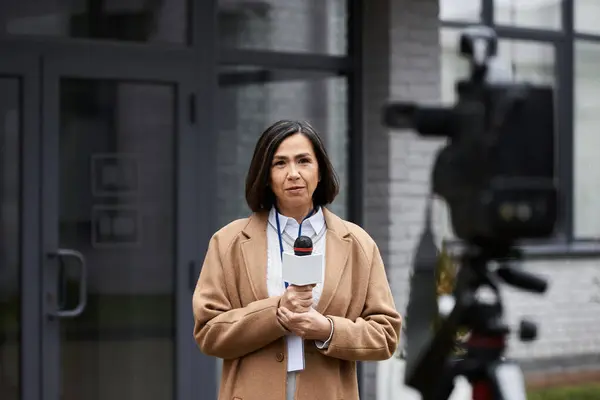 A journalist stands confidently outside, microphone in hand, ready to deliver important news coverage. — Stock Photo