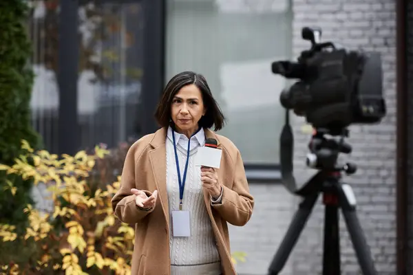 Una giornalista multirazziale parla in un microfono, catturando l'essenza delle ultime notizie fuori. — Foto stock