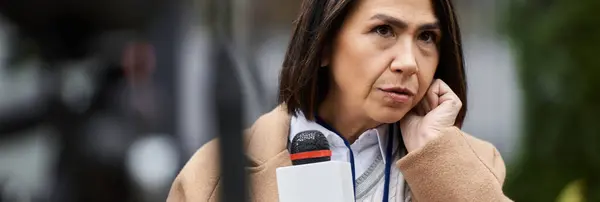 Una giornalista multirazziale femminile tiene un microfono mentre si prepara a consegnare gli ultimi aggiornamenti delle notizie. — Foto stock