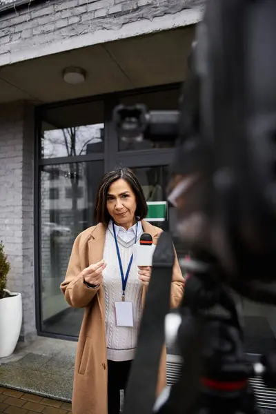 Um jornalista qualificado está pronto para transmitir a partir de um local da cidade, segurando um microfone com confiança. — Fotografia de Stock