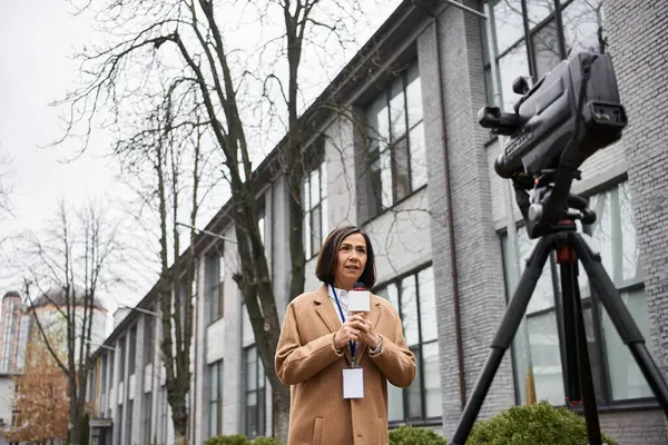 Une journaliste multiraciale tient un microphone et rapporte en plein air, montrant son professionnalisme. — Photo de stock