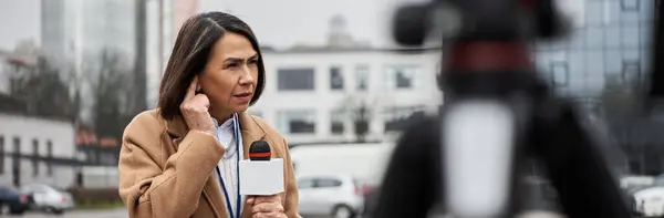 Uma jornalista multirracial fala em um microfone enquanto se prepara para uma reportagem ao vivo ao ar livre. — Fotografia de Stock