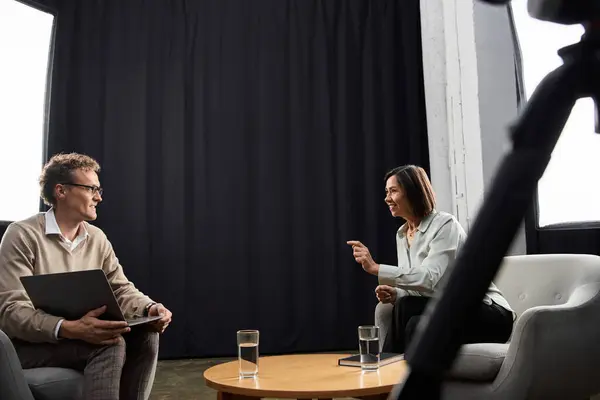 A middle-aged journalist is interviewing a specialist man in a cozy indoor setting, engaged and attentive. — Stock Photo