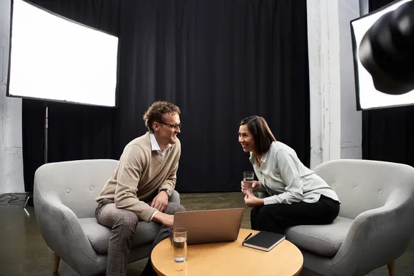 A middle-aged journalist and a male specialist share a lively conversation in a modern studio setting. — Stock Photo