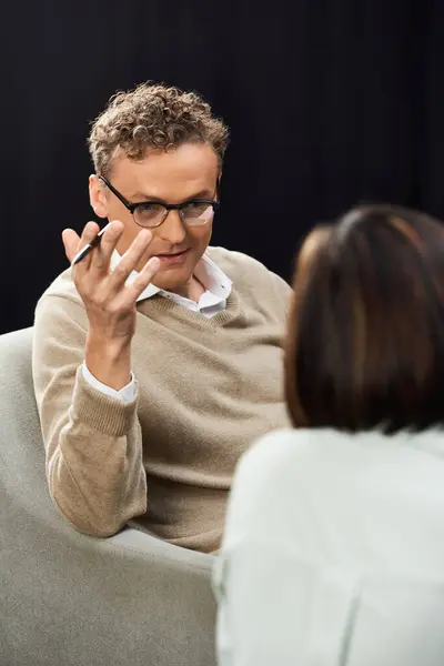 A journalist with glasses questions a woman specialist in a relaxed setting, focusing on an insightful conversation. — Stock Photo