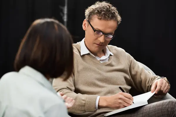 A journalist interviews a professional specialist, actively taking notes during their insightful discussion. — Stock Photo