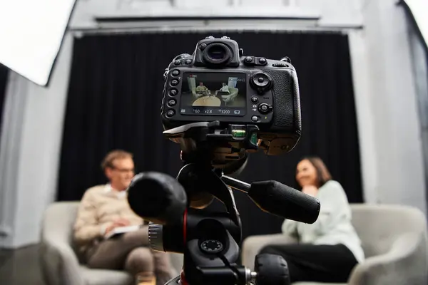 Em um estúdio moderno, um jornalista entrevista atentamente uma mulher conhecedora, promovendo um diálogo perspicaz. — Fotografia de Stock