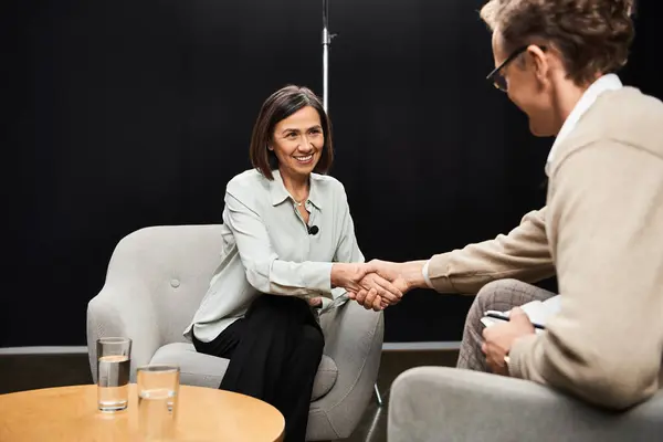 During an engaging dialogue, a journalist shakes hands with a specialist in a contemporary interview space. — Stock Photo