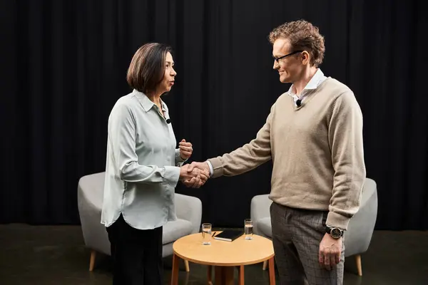 A journalist and a woman specialist shake hands, preparing for an insightful discussion in a warm space. — Stock Photo