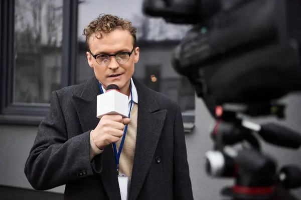 Un giornalista professionista parla in un microfono, riferendo in diretta da fuori città. — Foto stock