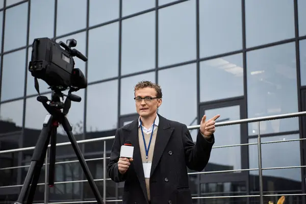 Un giornalista professionista che indossa occhiali riporta in diretta, interagendo con gli spettatori mentre è di stanza all'aperto. — Foto stock