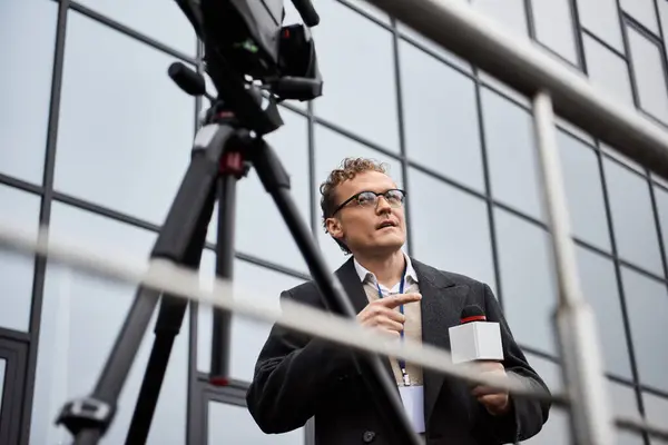 A professional journalist in glasses engages with a microphone, capturing news on location. — Stock Photo