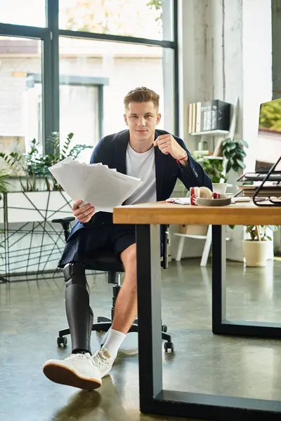 Un uomo giovane e professionale con una gamba protesica si concentra sul suo lavoro in un ambiente ufficio contemporaneo. — Foto stock