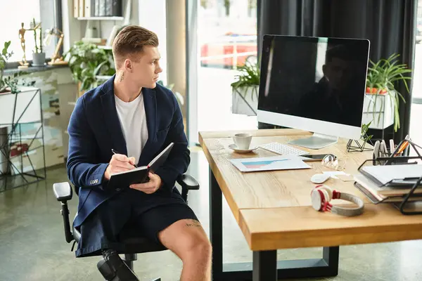 A young, determined man with a disability engages thoughtfully at his workspace in a contemporary office setting. — Stock Photo