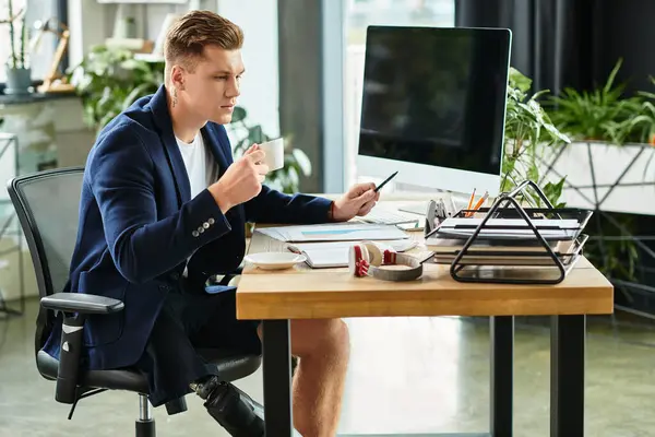 A young professional with a prosthetic limb focuses on tasks at a contemporary office desk filled with work. — Stock Photo