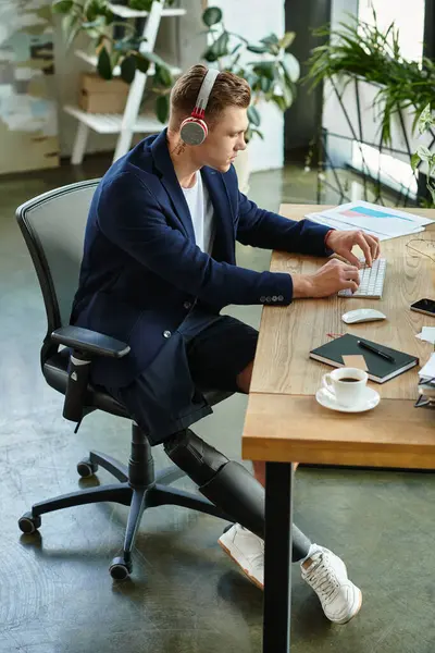 A determined young professional with a prosthetic limb focuses on his work at a contemporary office desk. — Stock Photo