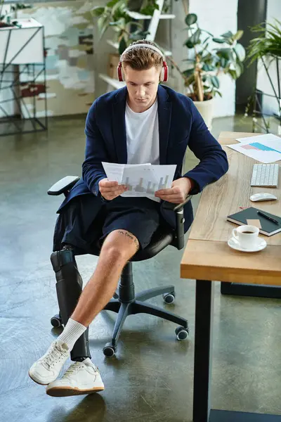 Un joven empresario decidido con una pierna protésica revisa informes importantes mientras trabaja. - foto de stock