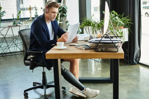 A focused young professional with an artificial limb engages in tasks at his stylish office workspace. — Stock Photo