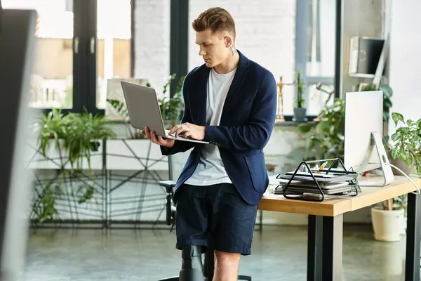 A young businessman with a prosthetic limb is focused on his laptop in a contemporary office. — Stock Photo