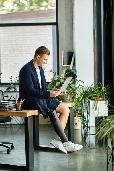 Um jovem empresário usando um laptop em um escritório vibrante, mostrando talento e inclusão com um membro artificial. — Fotografia de Stock