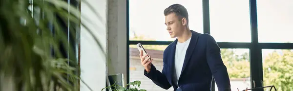 Молодой бизнесмен фокусируется на своем смартфоне, работая в ярком офисе. — стоковое фото