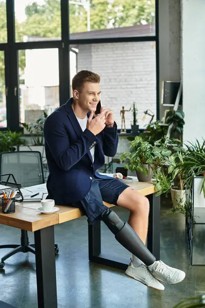 A confident young man with a prosthetic limb engages in a conversation while seated at his desk. — Stock Photo