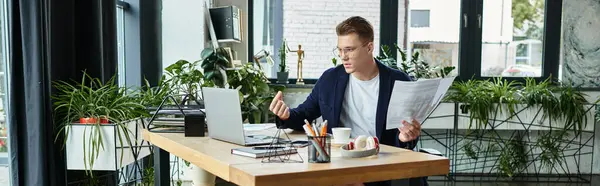 A young professional engages in work at a stylish office filled with greenery. — Stock Photo