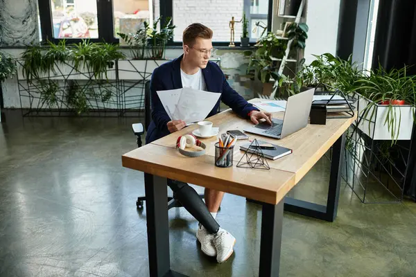 A young professional with a prosthetic limb focuses on his work at a stylish office desk, epitomizing determination. — Stock Photo