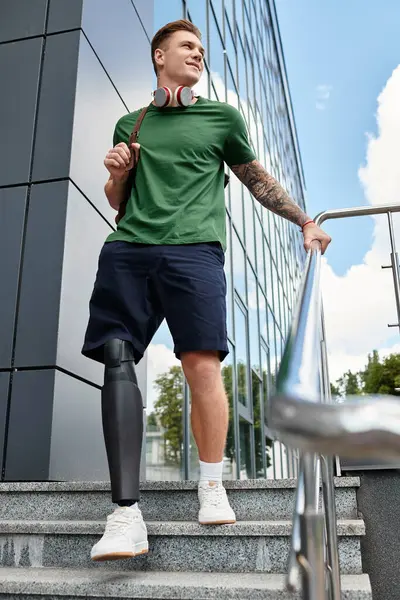 A smiling young man with a prosthetic leg stands on outdoor steps, embracing the sunny day with purpose. — Stock Photo
