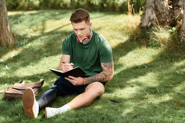 Un beau jeune homme avec une jambe prothétique aime créer de l'art dans un cadre luxuriant plein de verdure. — Photo de stock